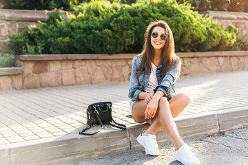Pretty young smiling brunette girl relaxing outdoor on the street.