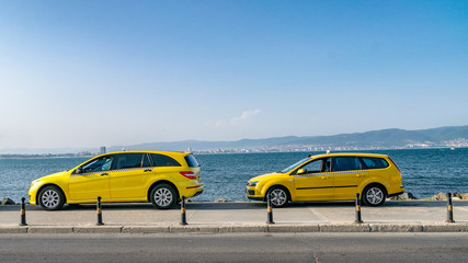 Yellow taxi cars on a street at see with water in the background. Yellow taxi cars on a beautiful...