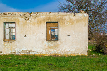 The ruins of an old earthen house without a roof. Holes in the wall at the site of windows and doors.