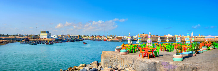 Landscape with colorful street cafe on quay of fishing port at Essaouira. Morocco, North Africa