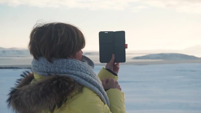 Happy woman taking pictures using smartphone, Iceland.