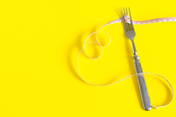 Diet concept. Fork on a white plate with centimeter. Time to lose weight , eating control or time to diet concept.