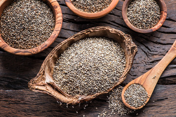 Chia seeds in different dishes on old wooden table. Top view.