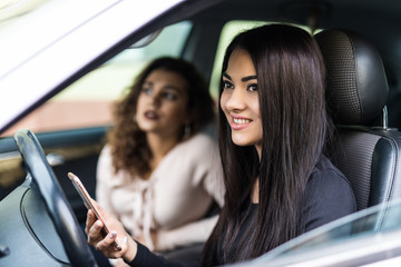Young woman takes control of a car while the driver using a mobile phone and losing concentration.