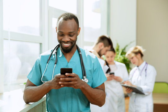 Healthcare people group. Professional african american male doctor with phone posing at hospital office or clinic. Medical technology research institute and doctor staff service concept. Happy smiling