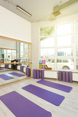 Empty space in fitness center, white brick walls, natural wooden floor and big windows, modern loft studio, yoga mats, comfortable open area for sport and exercises