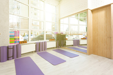 Empty space in fitness center, white brick walls, natural wooden floor and big windows, modern loft studio, yoga mats, comfortable open area for sport and exercises