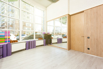 Empty space in fitness center, white brick walls, natural wooden floor and big windows, modern loft studio, yoga mats, comfortable open area for sport and exercises