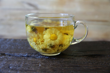 cup of chamomile tea with chamomile on rustic wooden background