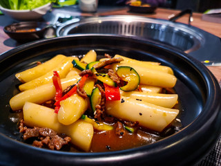 Korean Tteokbokki rice dumplings black dish in an korean ethnic restaurant with sweet ganjang soy sauce meat and zucchini bell peppers veggies