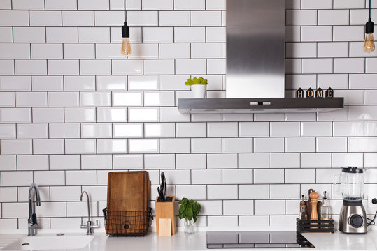 Modern kitchen with brick white tile wall and differet utensils