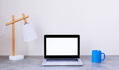 Front view of desktop with blank laptop and decorative items on wall background