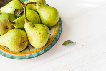 Fresh pears on a plate on white wooden table