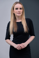 Studio portrait concept of a beautiful fashionable blond business girl standing and talking in a business dress against a multicolored background.