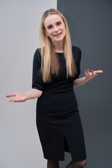 Studio portrait concept of a beautiful fashionable blond business girl standing and talking in a business dress against a multicolored background.