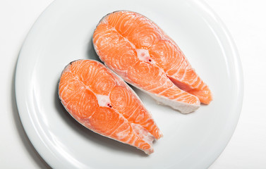 Two steaks of fresh salmon on a white plate. Raw red fish steak. Delicacy. Photos for sale of salmon and trout.