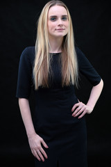 Fototapeta premium Studio portrait concept of a beautiful fashionable blond business girl standing and talking in a business dress on a black background.