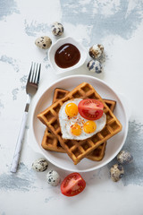 Belgian waffles and fried quail eggs, view from above on a white concrete background, vertical shot