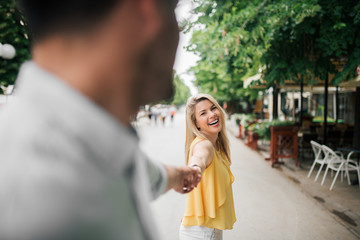 Couple in love. Smiling woman holding man's hand outdoors.