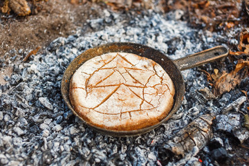 Cooking bread on fire coals in the evening