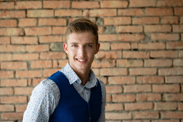 Guy model is standing by the brick wall and smiling