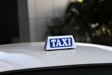 Taxi light sign or cab sign in white and blue color with white text on the car roof at the street...