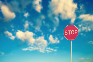 Red road stop sign on a blue sky background