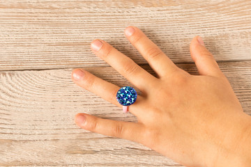 Funny ring on a little girl's hand. Isolated on wooden background.