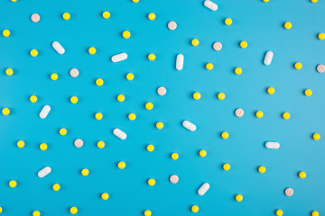 Yellow pills or capsules on a blue background with copy space.