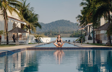 The Woman doing yoga exercise at poolside
