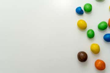 Close-up. Multicolored candies (dragees) in the glaze scattered on a white background. Place for text