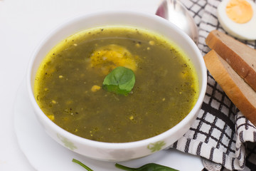Sorrel soup in white bowl with bread and leaves on white background. Top view, copy space for text