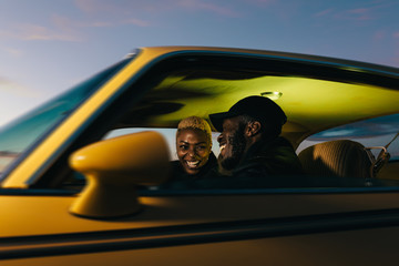 Cheerful black stylish couple having fun in the car