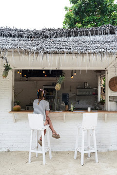 Woman customer having drink in a modern beach bar. Vacation.