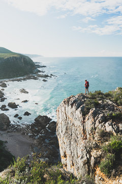 Hiker on a sea cliff overlooking a rugged scenic coastline