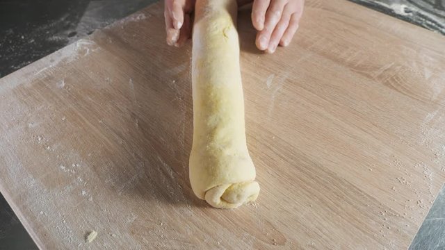 Baker chef working with dough on the table, close up.