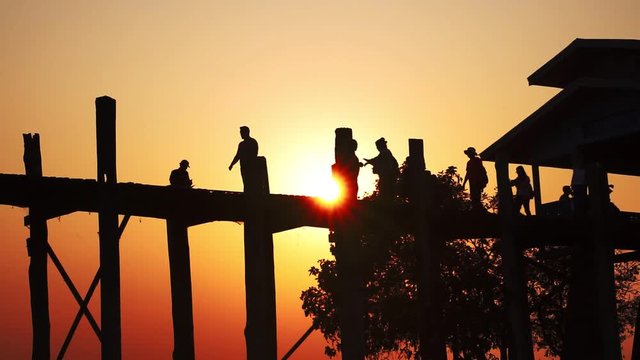 Silhouette of peoples at U-Bein oldes teakwood bridge in the world is made from the remains of a royal palace crossing Taungthaman Lake. Amarapura, Mandalay, Myanmar