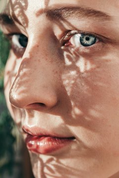 Close up portrait of young woman with floral shadows on her face