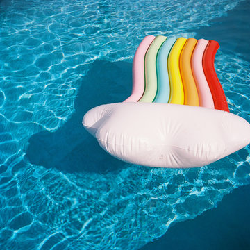 kids on rainbow floaty in blue pool on film