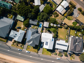 aerial view of  houses, with solar panels, swimming pool and the road