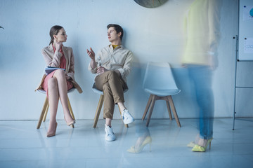 Obraz premium handsome employee with bottle of water sitting and talking with attractive woman