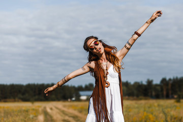 Pretty amazing free red-haired hippie girl dancing outdoors, feathers and braids in her hair, white...