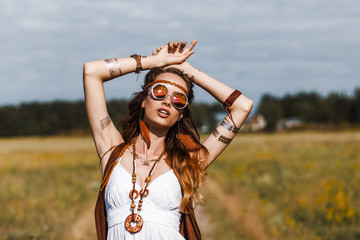 Pretty amazing free red-haired hippie girl dancing outdoors, feathers and braids in her hair, white dress, vest with fringe, accessories, sunglasses, tattoo flash, indie, Bohemian, boho style - obrazy, fototapety, plakaty