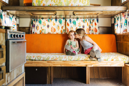 Cute toddler sisters sitting together in a vintage camper.