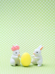 Two toy Easter Bunny and yellow egg. Easter holiday background, spring season. Easter decoration with rabbit and eggs, Easter idea, minimalist decor. Close up, Soft focus. copy space. 