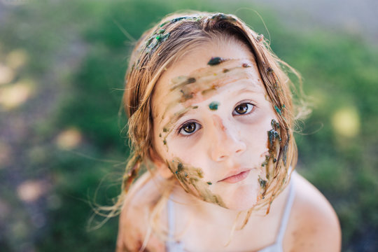 Toddler girl messy from painting herself with homemade paint.