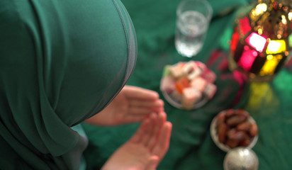 Muslim woman wearing hijab. Holy month of Ramadan. Dua (prayer) for breaking fast and beginning fast. Food and water. Praying, Islam, Religion © Fevziie