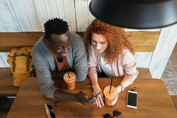 Couple chilling with drinks at cafe using phone