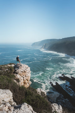 Hiker on a sea cliff outcrop taking in a scenic wilderness view