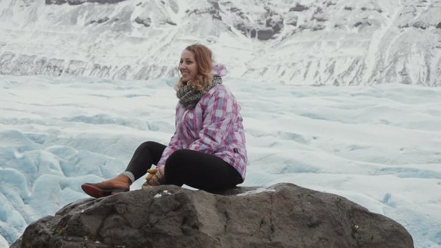 Iceland tourist sits and enjoying glacial in front of an icefield with some peaks in the background